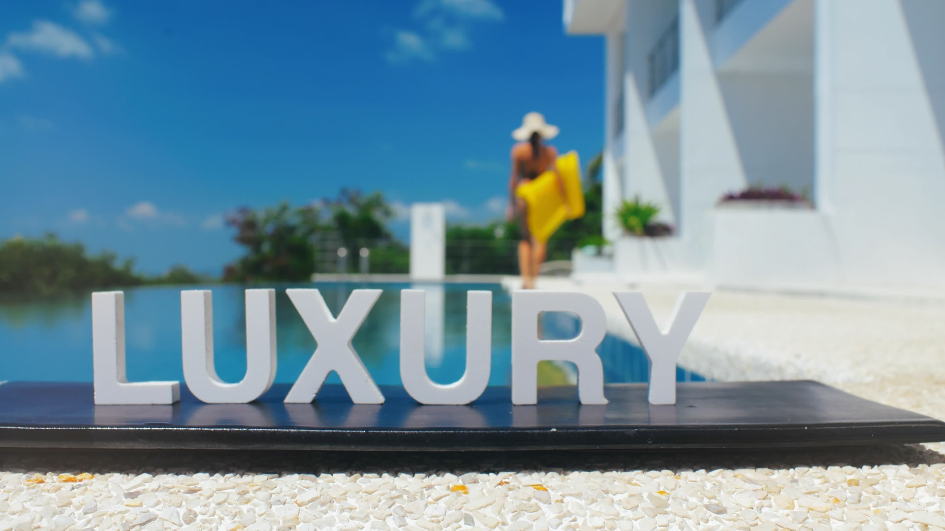 Woman in swimsuit with yellow mattress for floating walking on edge infinity